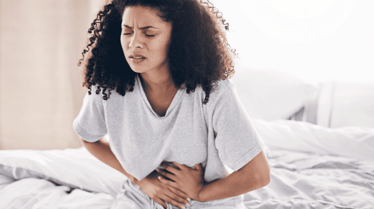 Bauchschmerzen, schwarze Frau im Bett mit Bauchkrämpfen, Magenschmerzen. Gesundheit, medizinischer Notfall Frau mit Verdauungsproblemen im Schlafzimmer.