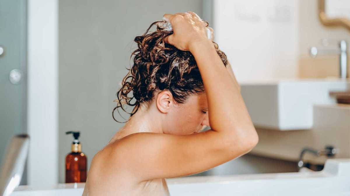Aufnahme einer Frau, die sich in der Badewanne die Haare shampooniert.