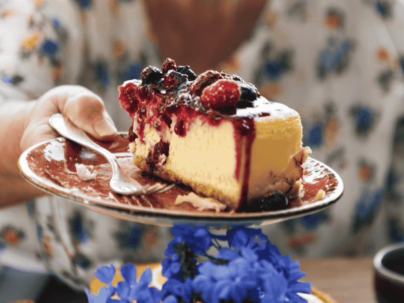 Oma reicht über den Tisch ein Teller mit Stück Käsekuchen.