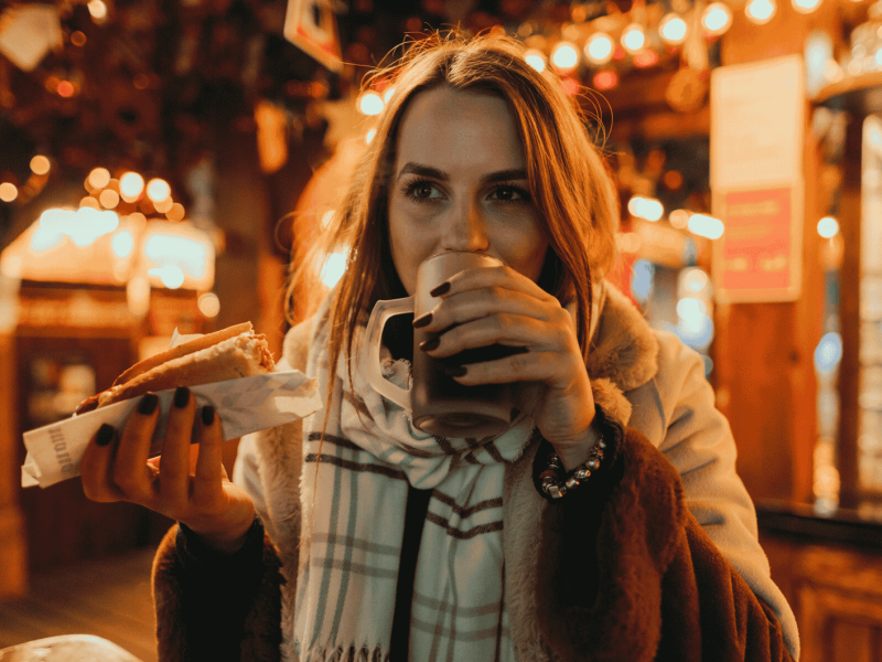 Frau trinkt Glühwein auf Weihnachtsmarkt.