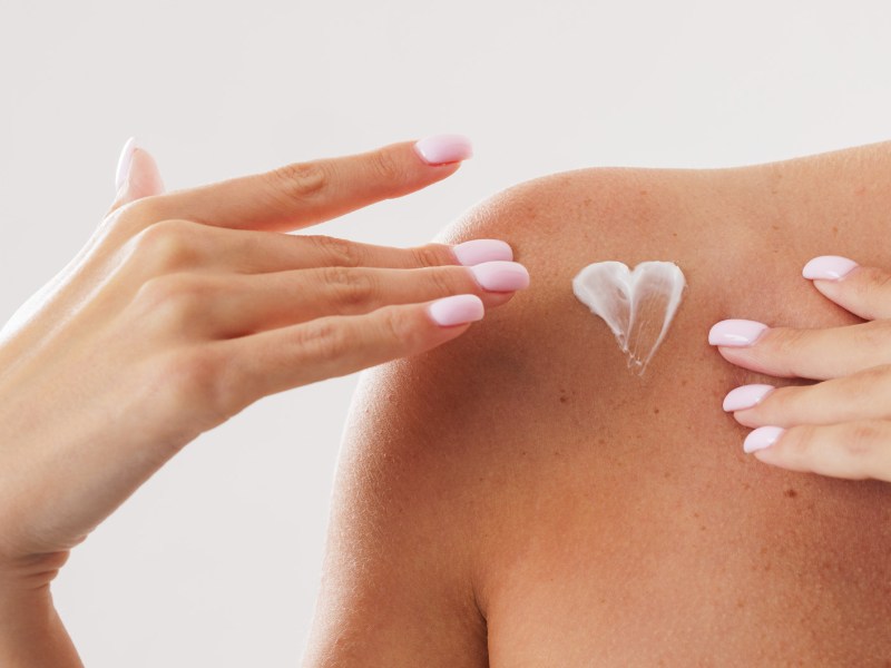 Frau mit einem Herz aus Hautcreme an der Schulter.