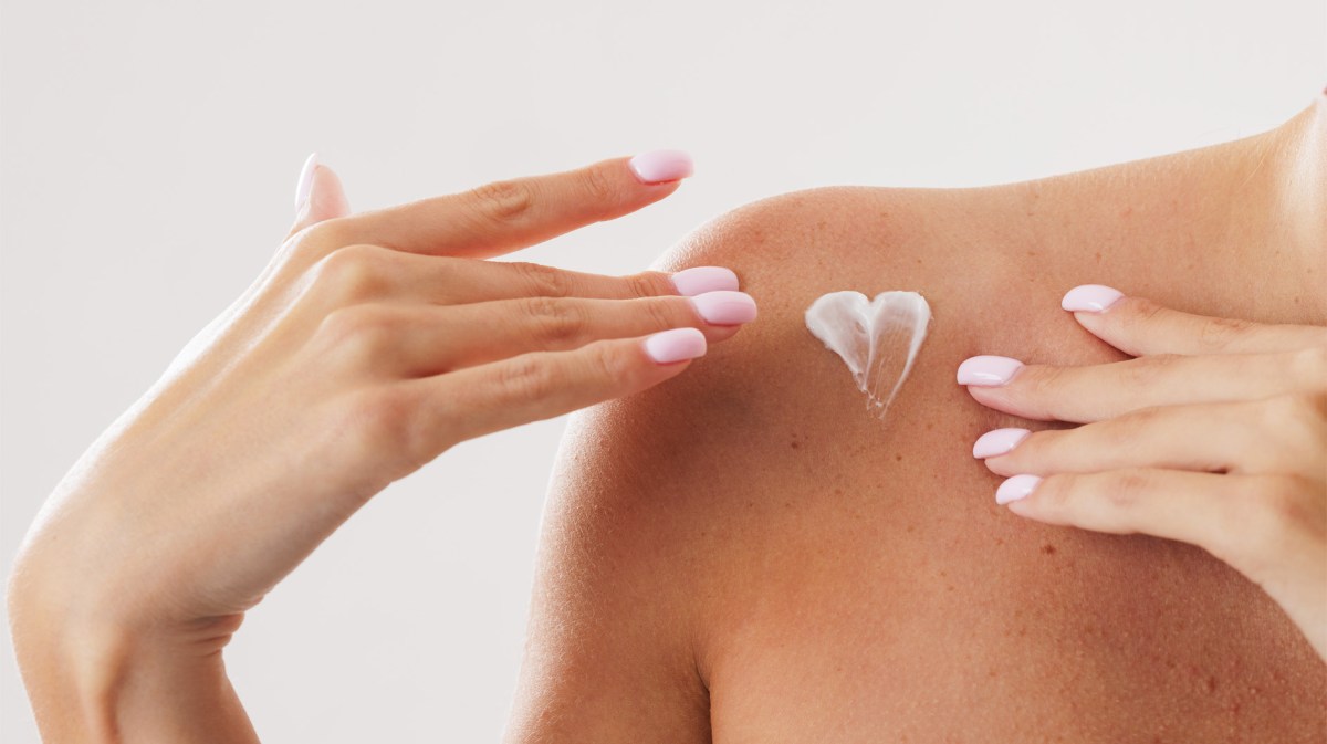 Frau mit einem Herz aus Hautcreme an der Schulter.
