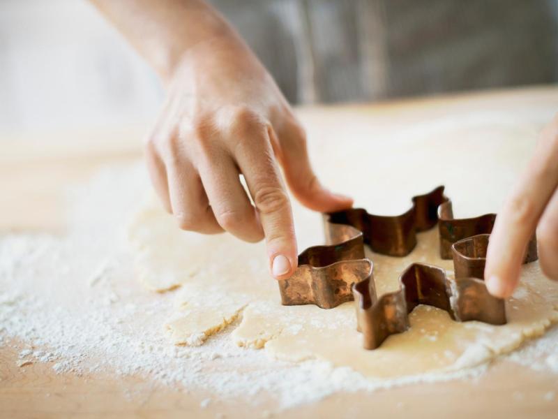 Frau sticht einen Stern aus Mürbeteig aus.