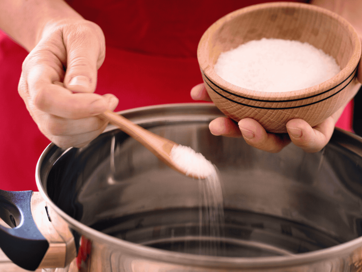 Frau gibt Salz ins Kochwasser.