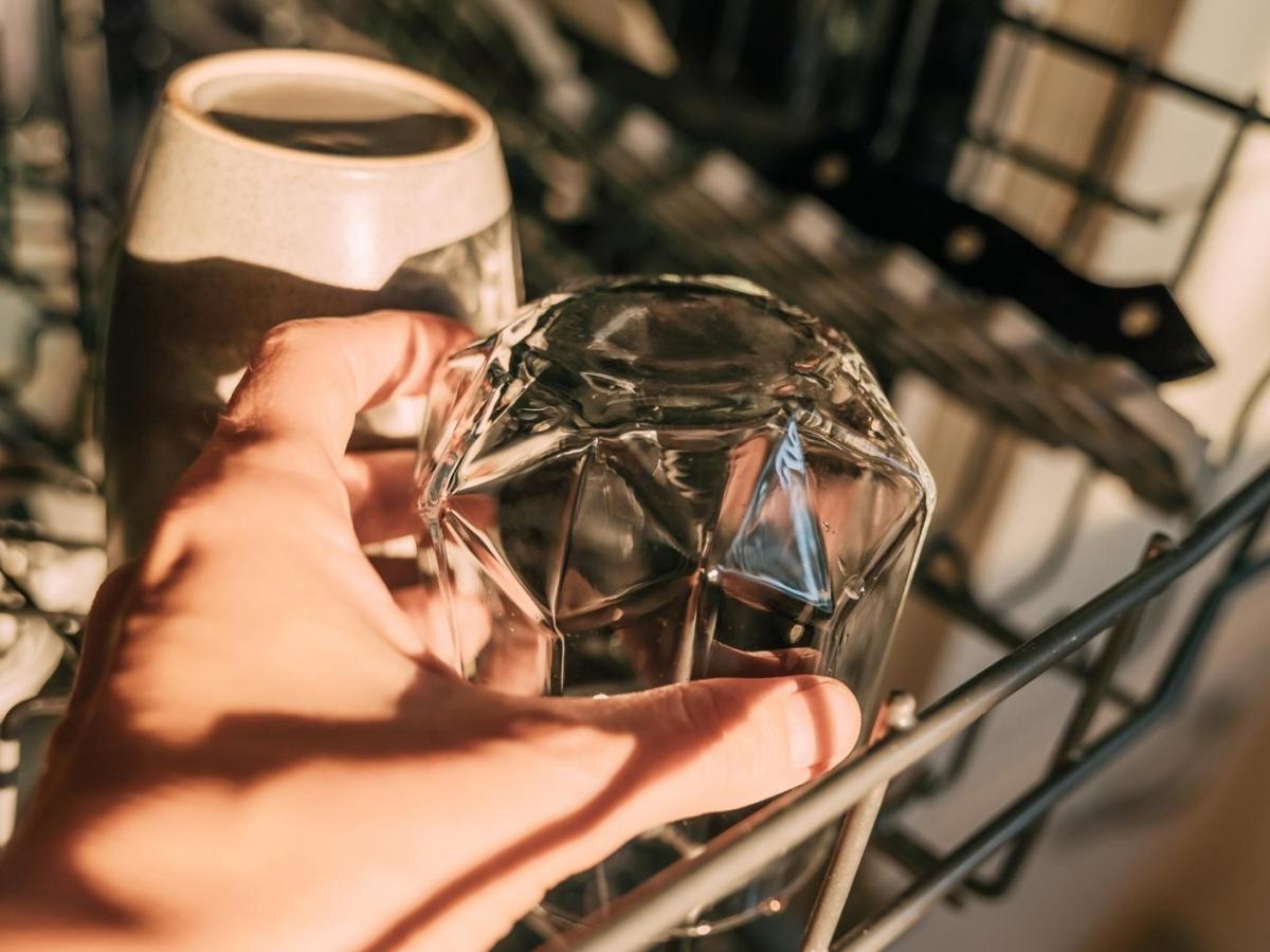 Frau r&auml;umt ein Glas in die Sp&uuml;lmaschine.