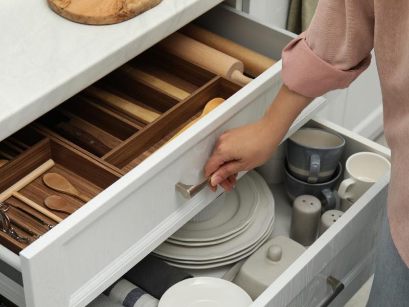 Frau öffnet eine gut sortierte Küchenschublade.