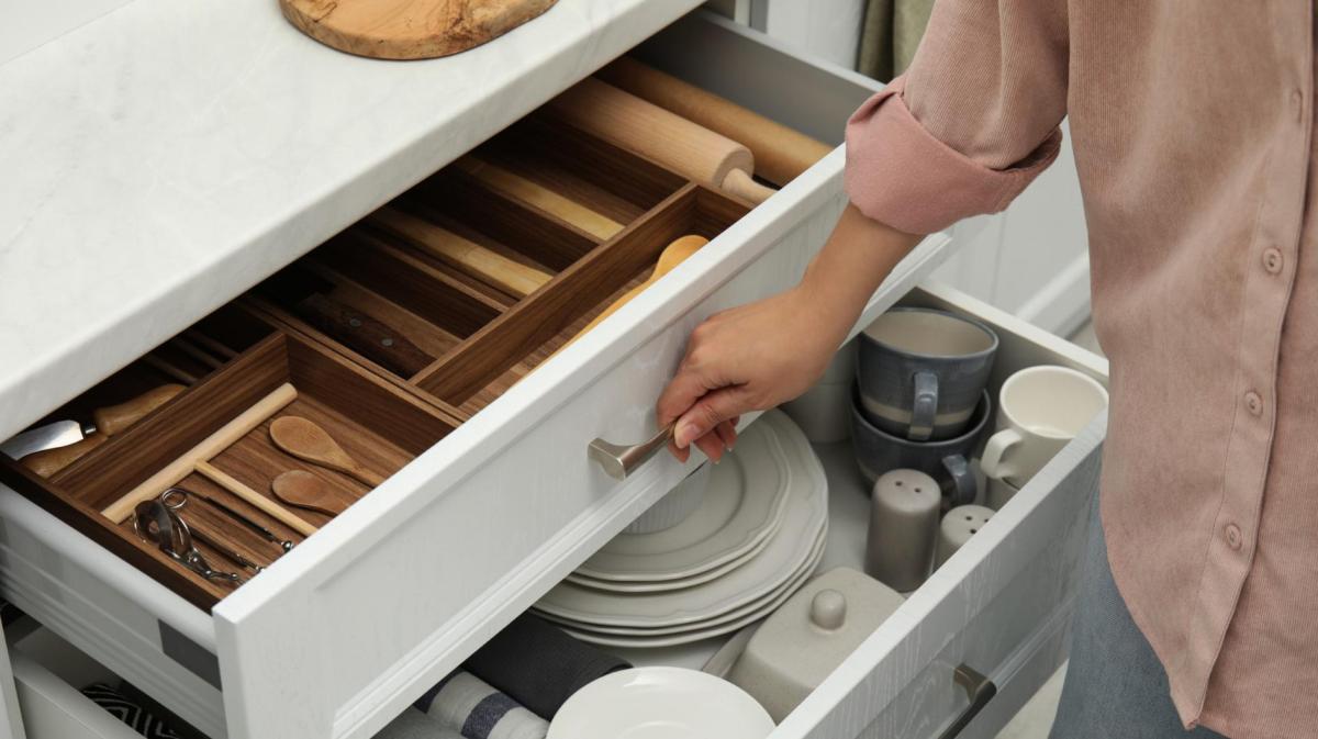 Frau öffnet eine gut sortierte Küchenschublade.