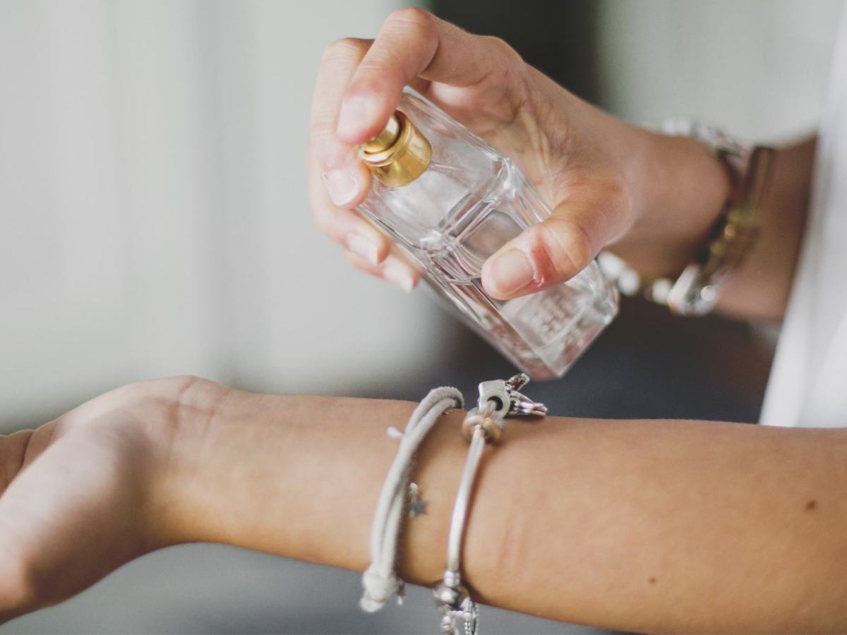 Frau sprüht sich ein Parfum auf den Arm.
