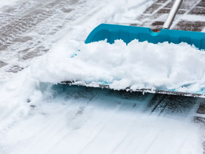 T&uuml;rkisblauer Schneeschieber befreit den Gehweg von Schnee