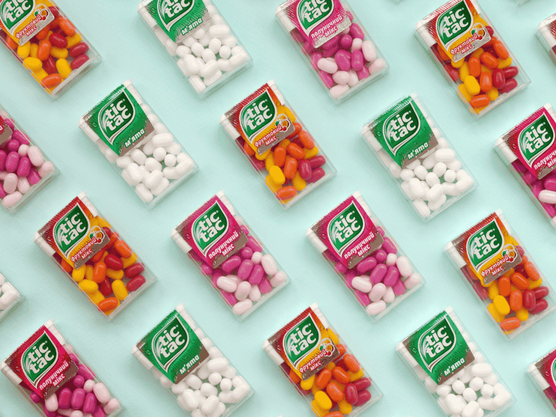 Mehrere Tic-Tac-Packungen liegen auf einem grünen Untergrund.