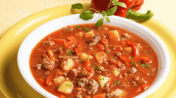 Bauerntopf mit veganem Hackfleisch, Kartoffeln, Paprika und Tomaten in einer wei&szlig;en Sch&uuml;ssel.