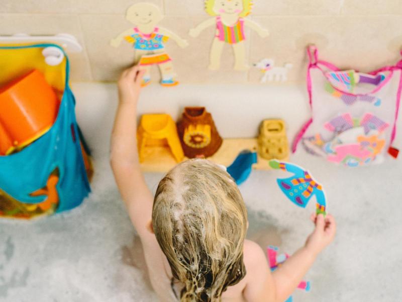 Kind spielt mit Wasserspielzeug in der Badewanne.
