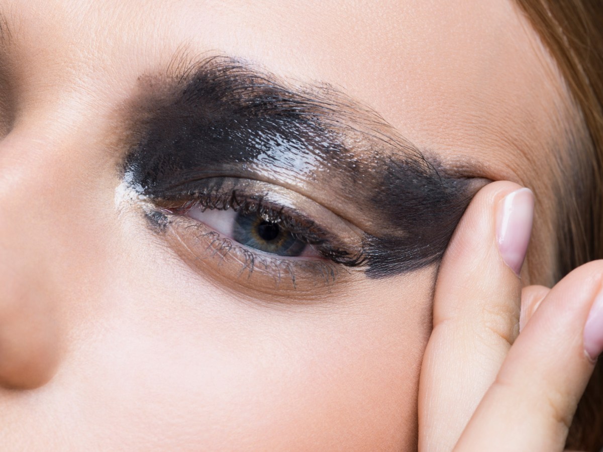 Frau mit verschmierter Wimperntusche am Auge