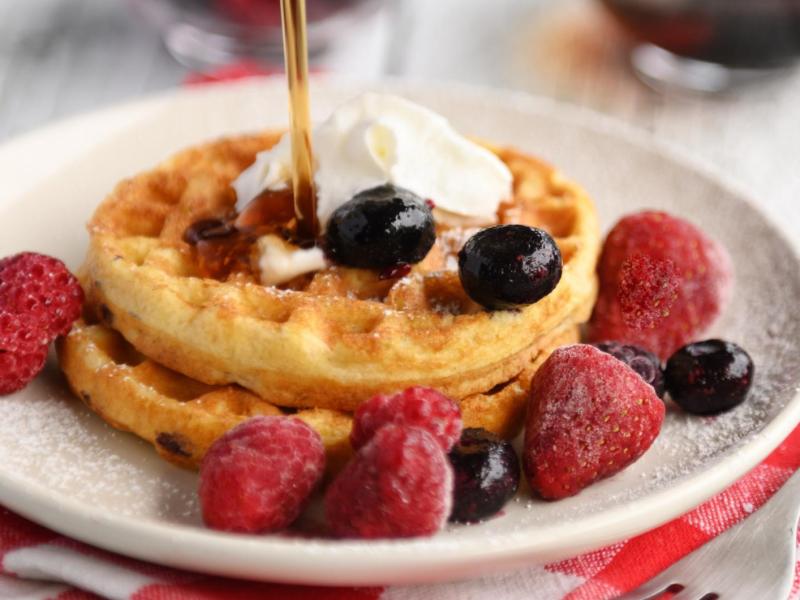 Mini-Waffeln auf einem Teller mit Früchten.