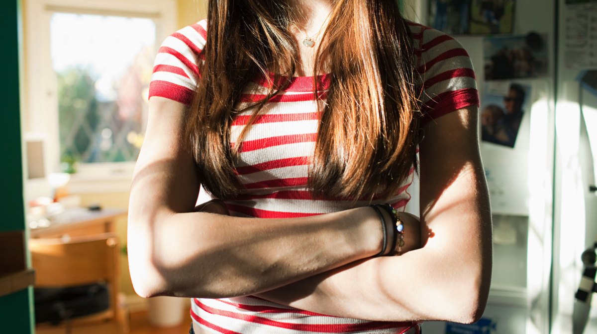 Teenager-Mädchen mit verschrenkten Armen.