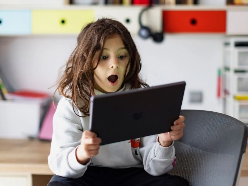 Junge sitzt mit Tablet in seinem Zimmer.