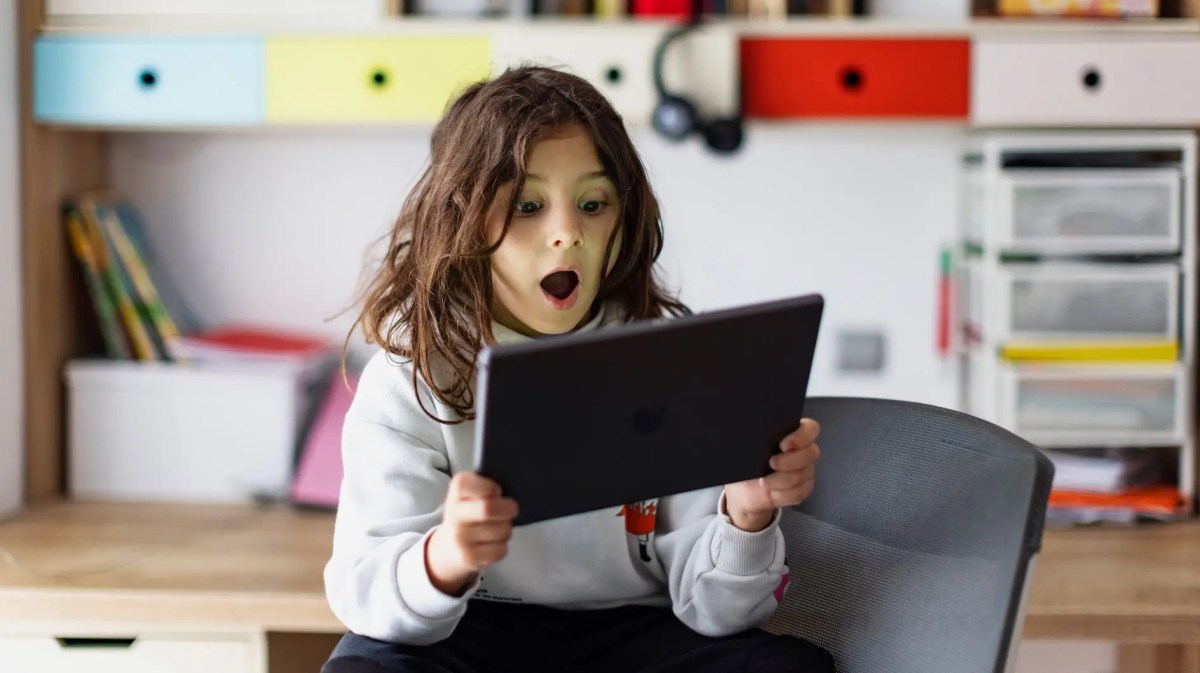 Junge sitzt mit Tablet in seinem Zimmer.