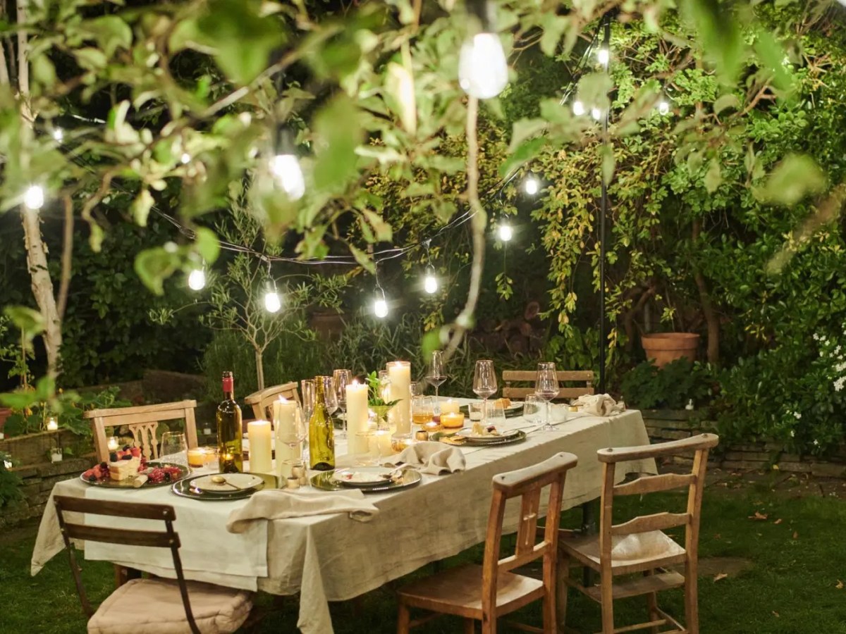 Ein gedeckter Tisch im Garten mit einer Lichterkette.