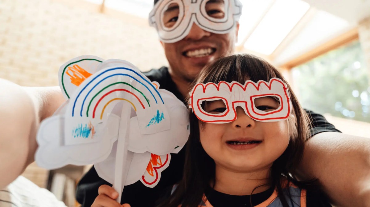 Tochter und Vater habn Masken gebastelt und machen ein Selfie.