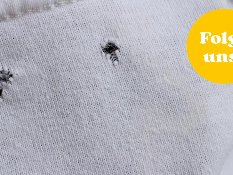 Kleine Löcher in weißem T-Shirt.