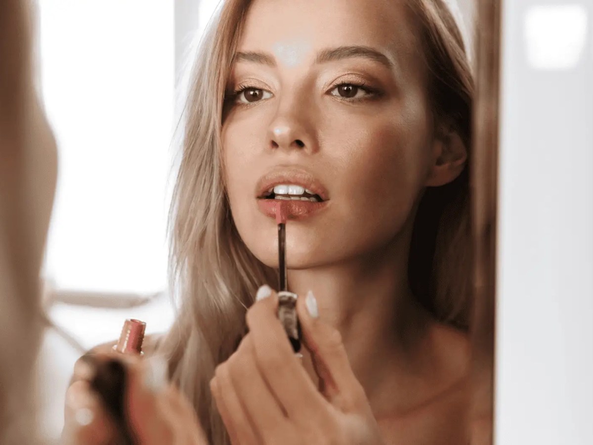 Junge Frau trägt Lippenstift auf.