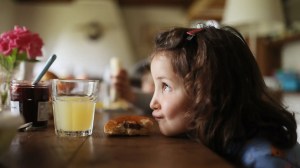 Mädchen, ca 5 Jahre, hat ihren Kopf auf dem Küchentisch abgelegt und zieht einen Schmollmund.