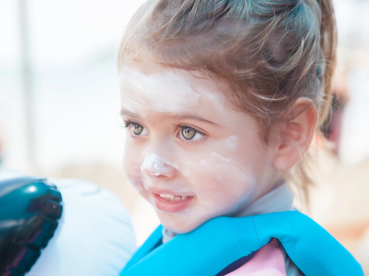 Kleines Mädchen etwa 5 Jahre mit Sonnencreme im Gesicht