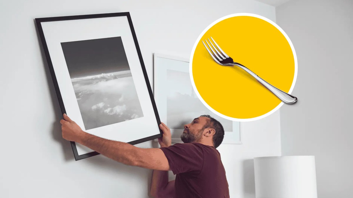 Mann hängt Bild an Wand auf.
