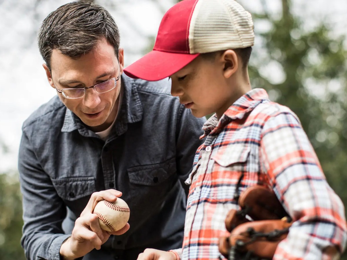 Vater erkl&auml;rt Sohn, wie er den Baseball richtig wirft.