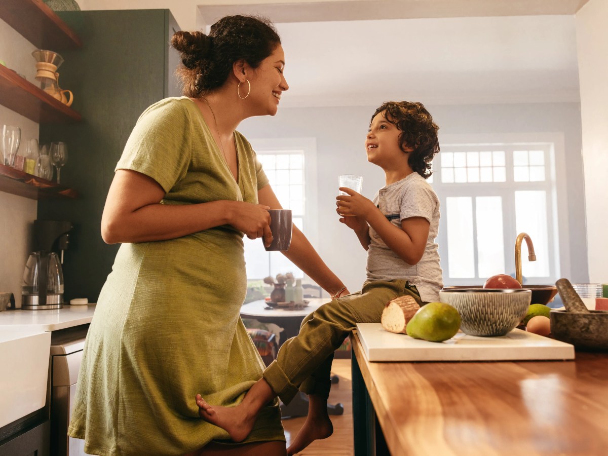 Mutter und Sohn sitzen in der K&uuml;che und lachen sich an