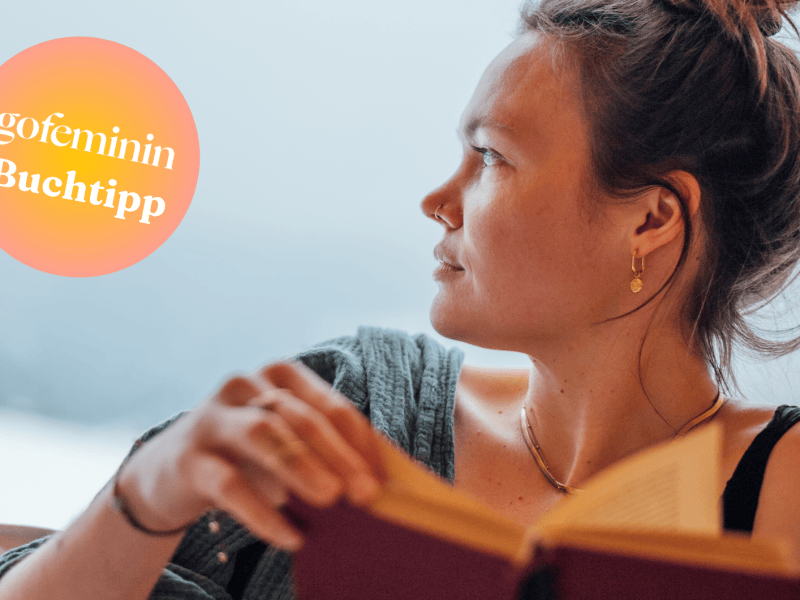 Frau mit einem Buch in der Hand schaut zur Seite