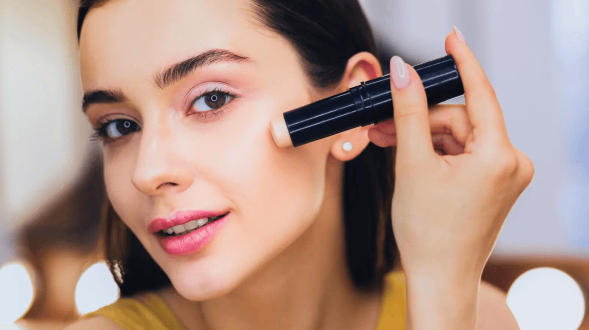 Frau, die mit einem Stift Make-up aufträgt.